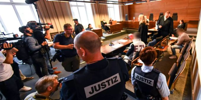 Der wegen Kindesmissbrauchs angeklagte Lebensgefährte (m., helle Weste) und die angeklagte Mutter (r.) sitzen umgeben von Anwälten, Polizisten und Journalisten in einem Saal des Freiburger Landgerichts. Der wegen Kindesmissbrauchs angeklagte Lebensgefährte (m., helle Weste) und die angeklagte Mutter (r.) sitzen umgeben von Anwälten, Polizisten und Journalisten in einem Saal des Freiburger Landgerichts.