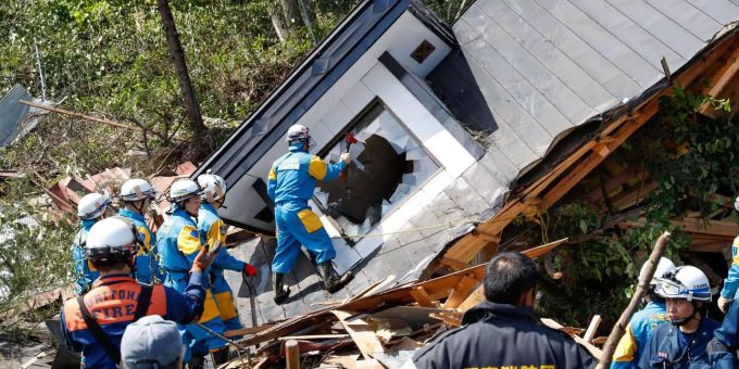 Polizisten (in blauer Uniform) und Rettungskräfte suchen in einem bei einem Erdrutsch zerstörten Haus auf der japanischen Insel Hokkaido nach vermissten Bewohnern. Polizisten (in blauer Uniform) und Rettungskräfte suchen in einem bei einem Erdrutsch zerstörten Haus auf der japanischen Insel Hokkaido nach vermissten Bewohnern.