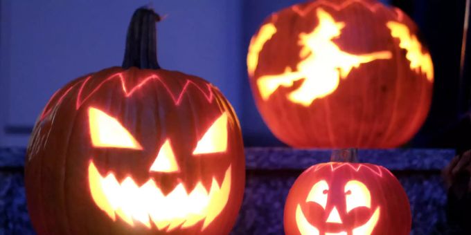 Geschnitzte Halloween-Kürbisse mit Geister-Motiven stehen von innen beleuchtet vor einem Haus. Geschnitzte Halloween-Kürbisse mit Geister-Motiven stehen von innen beleuchtet vor einem Haus.