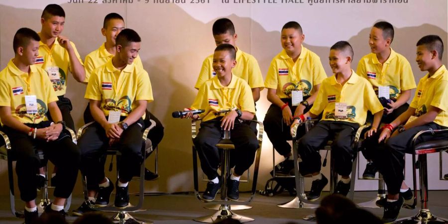 Spieler der Fussballmannschaft, die im Juli in einer riskanten Rettungsaktion aus einer Höhle in Thailand befreit wurden, lachen während eines öffentlichen Auftritts.
