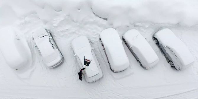 Ein Mann befreit sein Auto von Schnee