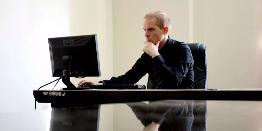 Ein Mann sitzt leicht gebeugt vor dem PC.