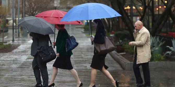 Menschen mit Regenschirmen gehen in Sacramento durch den Regen.