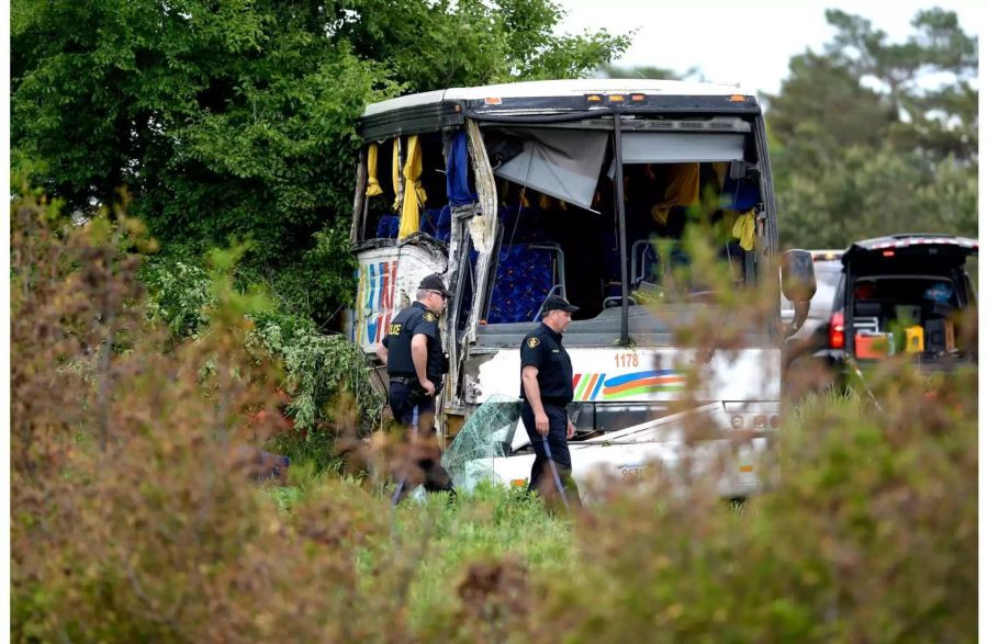 Polizisten arbeiten nach einem Unfall mit einem Reisebus an der Unfallstelle.