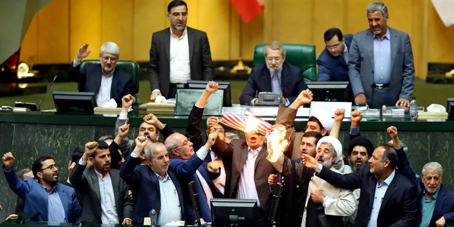 Iranische Parlamentarier bejubeln das Verbrennen einer US-Flagge.