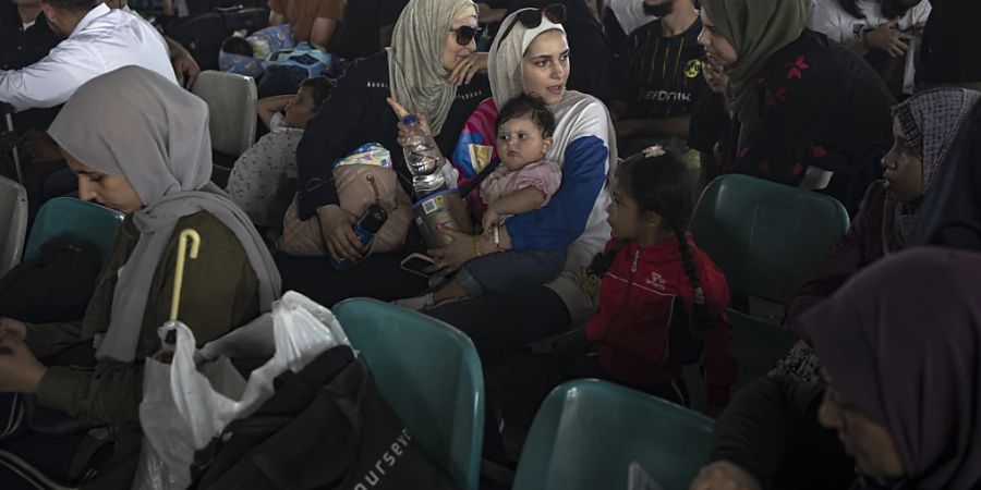 Menschen warten am Grenzübergang zwischen dem Gazastreifen und Ägypten. Verletzte Palästinenser und Inhaber ausländischer Pässe können über den Grenzübergang Rafah evakuiert werden. Foto: Fatima Shbair/AP/dpa