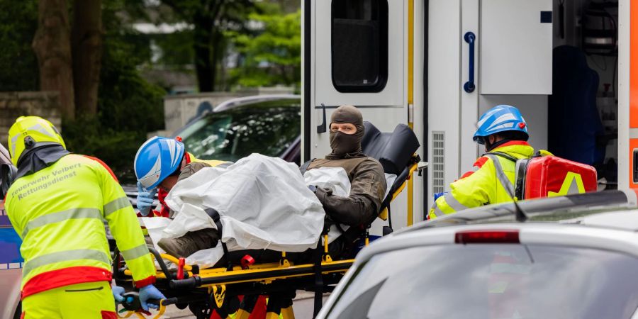 Ein verletzter Polizeibeamter wird vor einem Hochhaus in einen Krankenwagen gebracht.