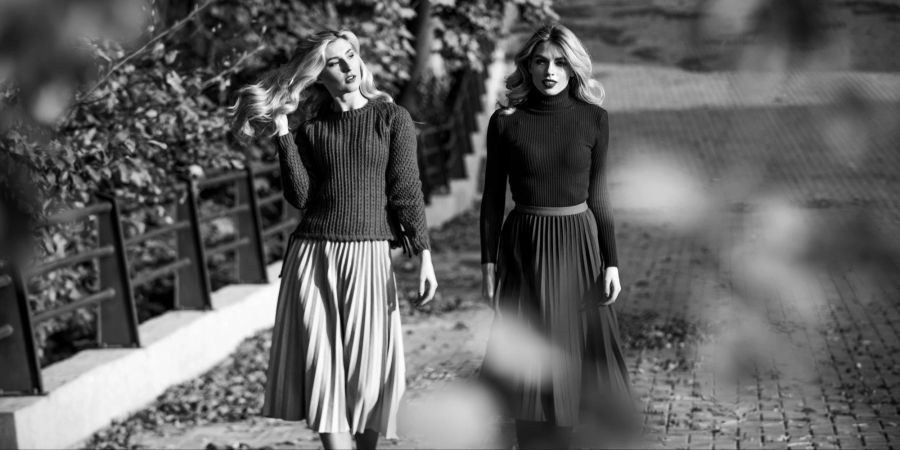 Schwarz Weiss zwei Frauen in langen Röcken gehen Strasse entlang.