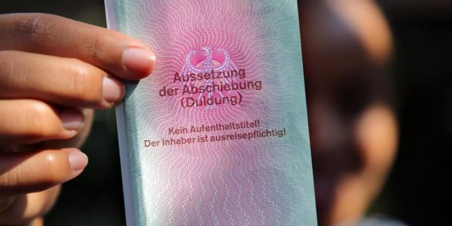 Eine junge Frau hält einen Ausweis für Flüchtlinge in der Hand mit dem Titel: Aussetzung der Abschiebung (Duldung). Foto: Wolfgang Kumm