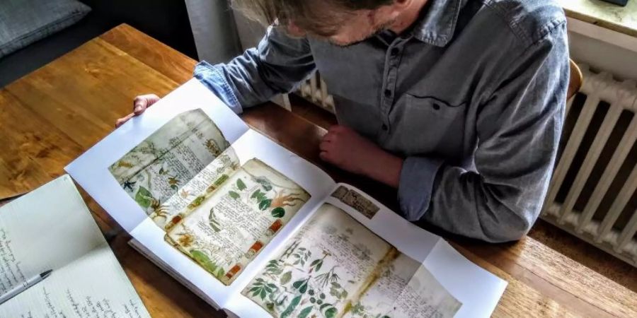 Der Computerlinguistiker Jürgen Hermes mit einem Faksimile des berühmten Voynich-Manuskripts. Foto: Privat Jürgen Hermes/dpa