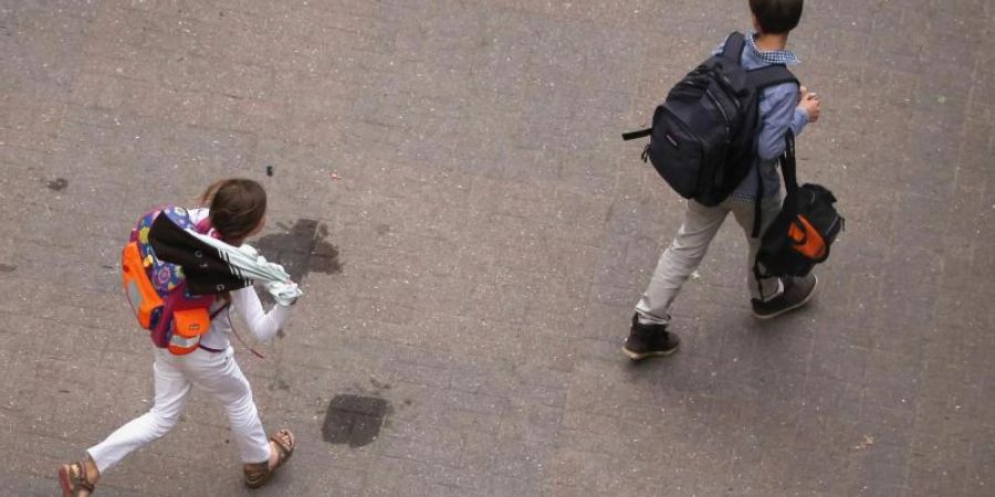 Zwei Schüler gehen über den Hof einer Schule. Foto: Christian Charisius/Illustration