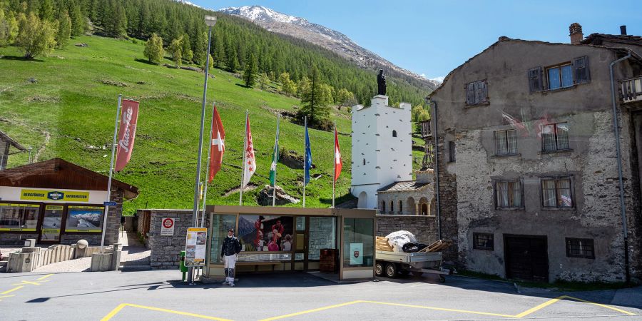 Die Postautohaltestelle im Dorfzentrum von Saas-Grund mit der Friedhofskapelle der Pfarrei St. Bartholomäus.