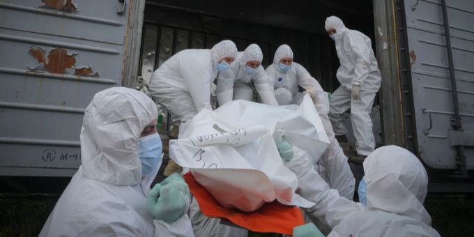 Ukrainer laden die Leiche eines russischen Soldaten in einen Kühlzug. putins