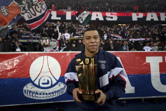Kylian Mbappé feiert sein Rekordtor mit der Trophäe. PSG
