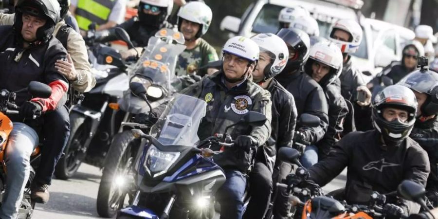 Bolsonaro in der Karawane von Motorradfahrern auf ihrem Weg durch Sao Paulo. Erst vor drei Wochen hatte Bolsonaro ohne Mund-Nasen-Schutz an einer Motorradrundfahrt durch die Millionenmetropole Rio de Janeiro teilgenommen und eine Rede vor seinen Anhängern gehalten. Foto: Marcelo Chello/AP/dpa