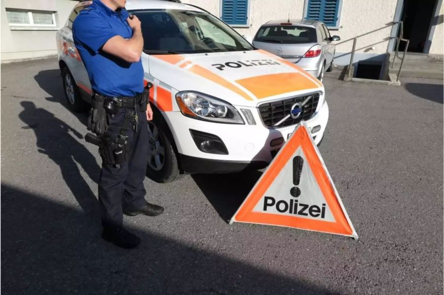 Polizist der Kantonspolizei Glarus mit einem Polizeiwagen und einem Polizei Warndreieck - zvg Kantonspolizei Glarus