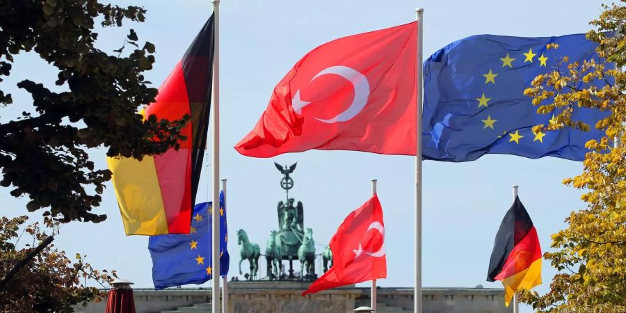 Die Flaggen der Bundesrepublik Deutschland, der Türkei und Europas wehen vor dem Brandenburger Tor im Wind.