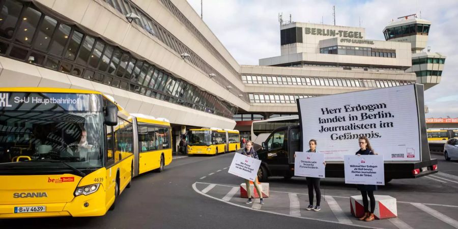 Ein Bus fährt auf dem Flughafen Berlin Tegel an Demonstranten der Organisation Reporter ohne Grenzen vorbei.