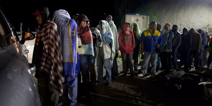 Migranten aus Kolumbien stehen in einer Reihe, um Brot und Kaffee zu holen.