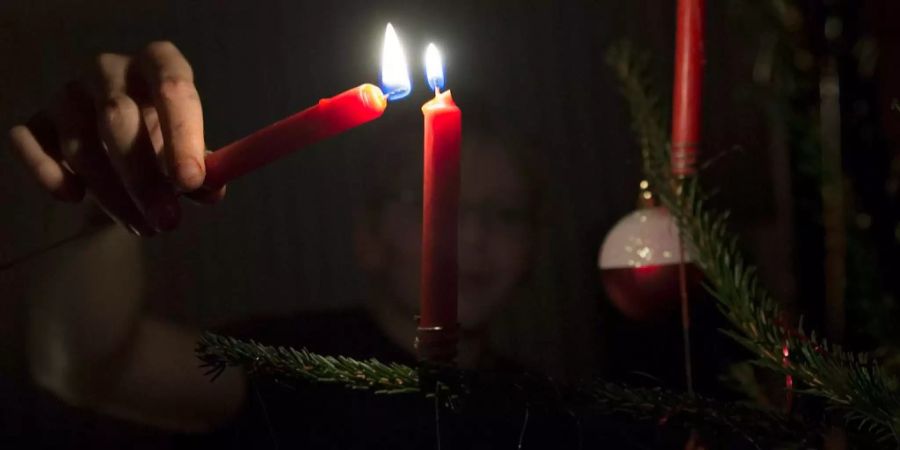 Joel Schneider entzündet Kerzen am Christbaum an Heiligabend.