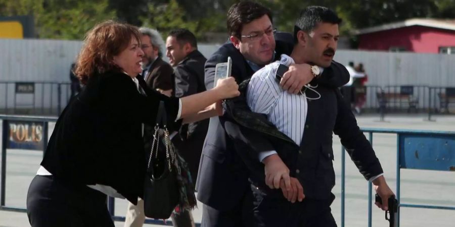 Dilek Dündar (l), Frau vonCan Dündar, und Muharrem Erkek versuchen Murat Sahin (r) festzuhalten.