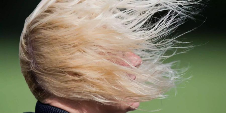 Die Haare einer Person werden von einer Windböe erfasst.