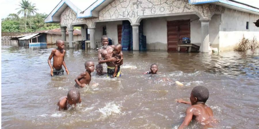 Kinder spielen nach Überschwemmungen im Niger im Wasser.