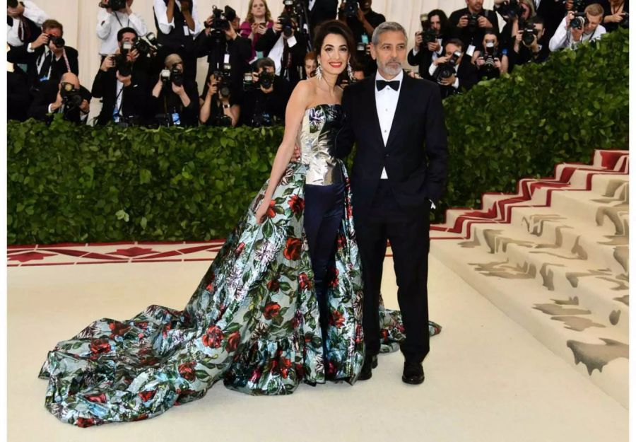 Amal zieht die Blicke auf ihr extravagantes Outfit, Ehemann George Clooney mag es eher schlicht.