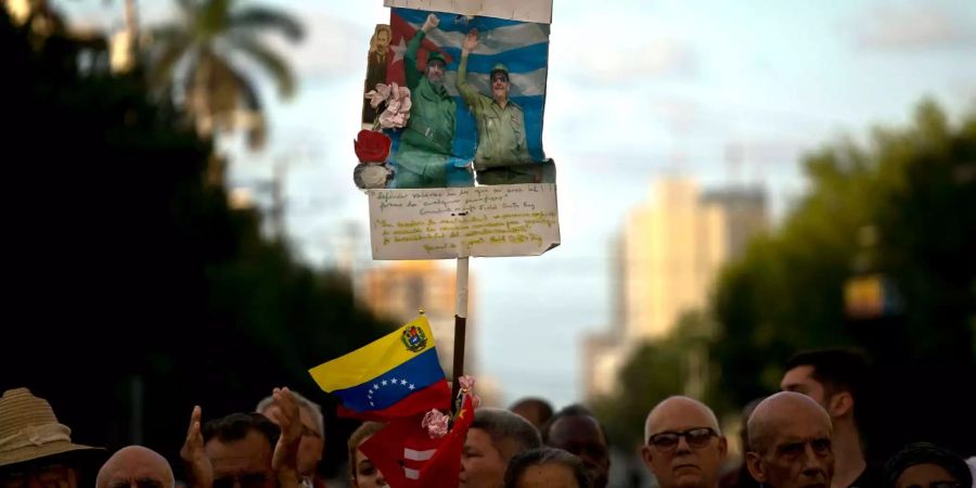 Menschen halten ein Plakat mit einem Bild von Fidel Castro (l), ehemaliges Staatsoberhaupt von Kuba, und Raul Castro, Staatsoberhaupt von Kuba.