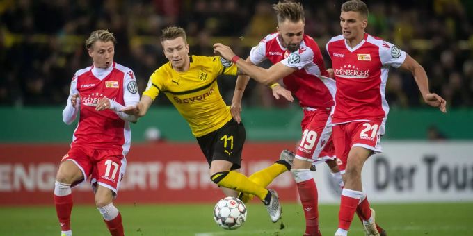 Dortmunds Marco Reus (2.v.l.) und Unions Simon Hedlund, Florian Hübner und Grischa Prömel (l.-r.) versuchen an den Ball zu kommen. Reus schoss das Siegestor in der Nachspielzeit. Borussia Dortmunds Marco Reuss (2.v.l.) umspielt drei Spieler der Union Berlin.