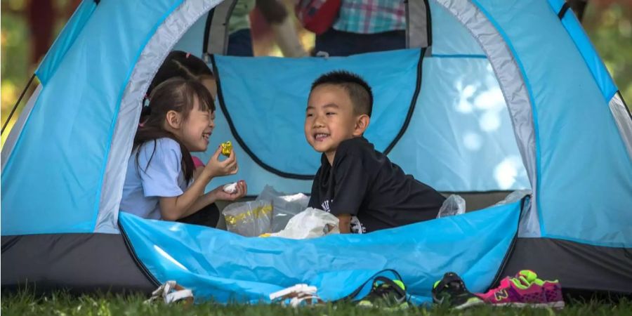 Chinesische Kinder spielen in einem Zelt.