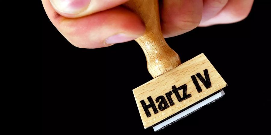 Eine Hand hält einen Stempel mit der Aufschrift «Hartz IV».