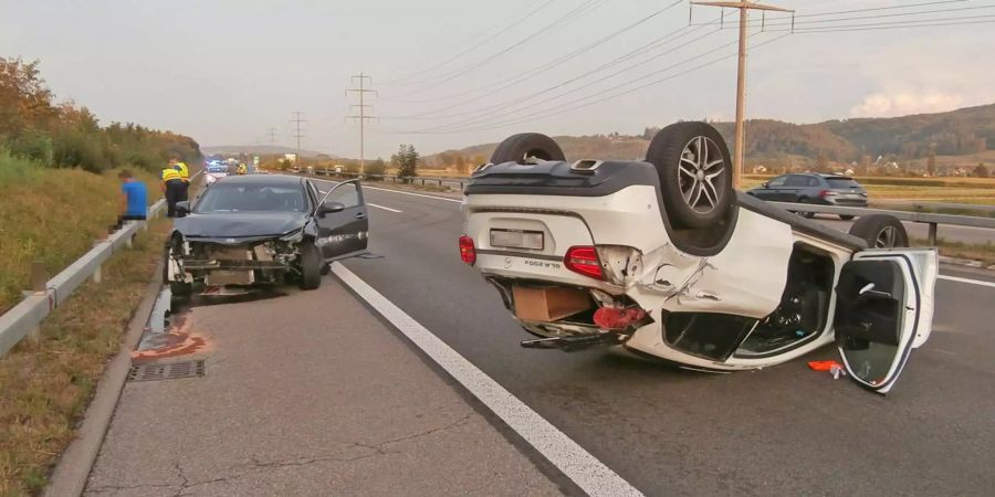 Die beiden in den Auffahrunfall auf der A7 bei Hüttlingen TG involvierten Fahrzeuge: Der schwarze KIA steht mit eingedrückter Motorhaube auf dem Pannenstreifen, der andere, weisse Wagen liegt auf der rechten Fahrspur auf dem Dach.