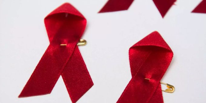 Rote Schleifen, weltweit anerkanntes Symbol für die Solidarität mit HIV-Infizierten, liegen auf einem Tisch. gericht hiv positive