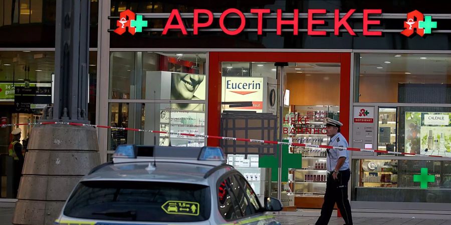 Ein Polizist steht vor der abgesperrten Apotheke im Kölner Hauptbahnhof.