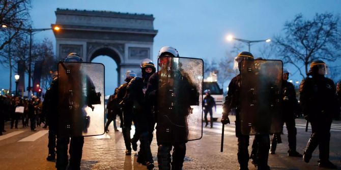 Polizisten gehen auf der Champs Elysees vor dem Triumphbogen.