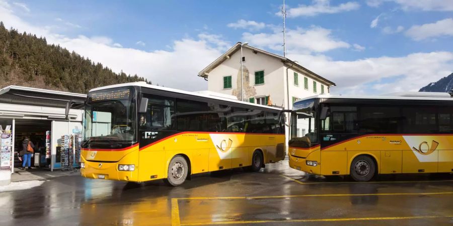 Postautos bei einem Bahnhof im Bündnerland.