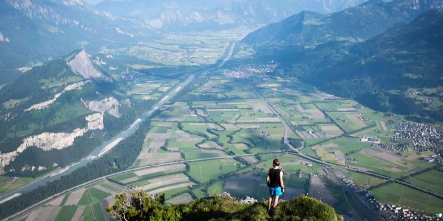 Ein Berggänger auf dem Gonzen bei Sargans blickt über die Aussicht ins St. Galler und Bündner Rheintal und auf dem Liechtenstein auf der anderen Rheinseite.