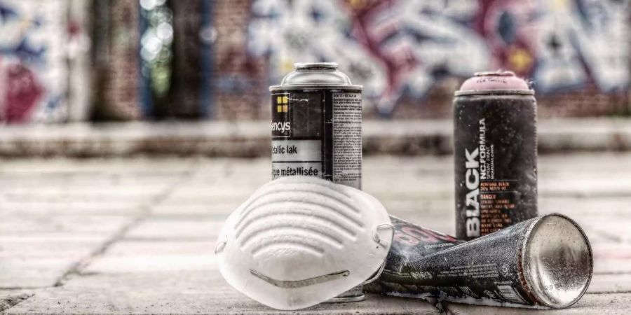 Das Equipment eines Sprayers: eine Atemschutzmaske und Sprühdosen.