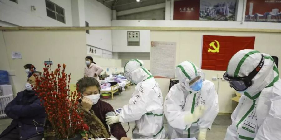 Medizinisches Personal in Wuhan betreut Patienten mit Symptomen des Coronavirus in einem provisorischen Krankenhaus. Foto: CHINATOPIX/AP/dpa