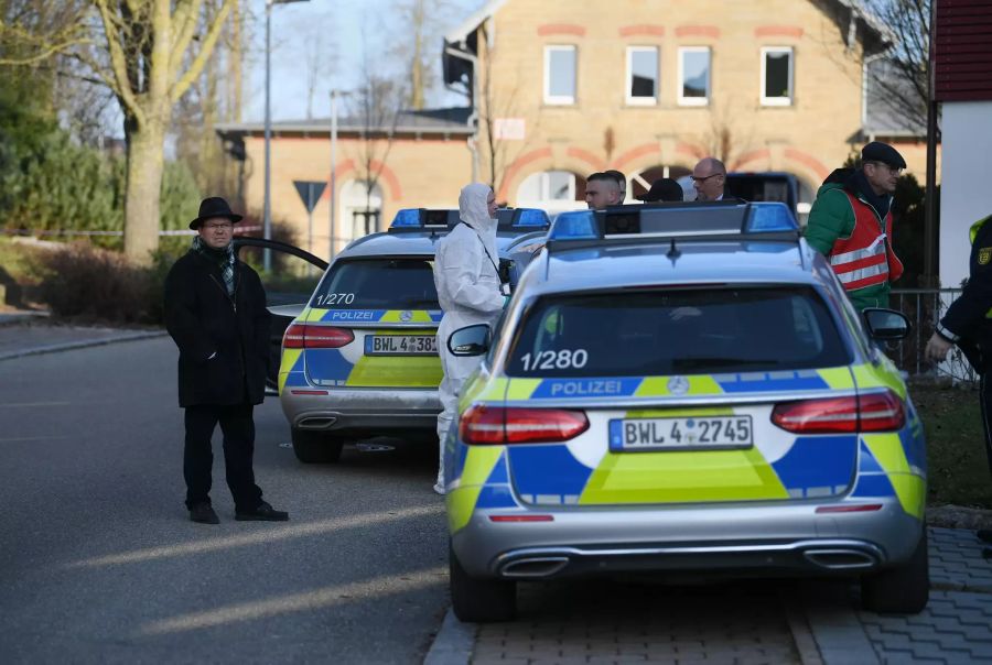 Nach Schüssen in Rot am See im Nordosten Baden-Württembergs stehen Polizeiautos an einem Haus.