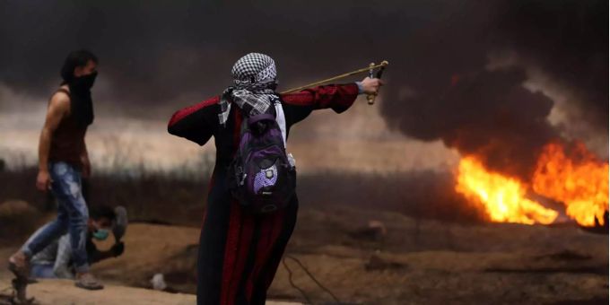 Eine Palästinenserin schleudert einen Stein in Richtung israelische Sicherheitskräfte an der Grenze von Israel. Eine Palästinenserin schleudert einen Stein in Richtung israelische Sicherheitskräfte an der Grenze von Israel.