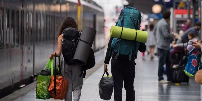 Junge Reisende gehen im Hauptbahnhof der Mainmetropole mit ihren Rucks