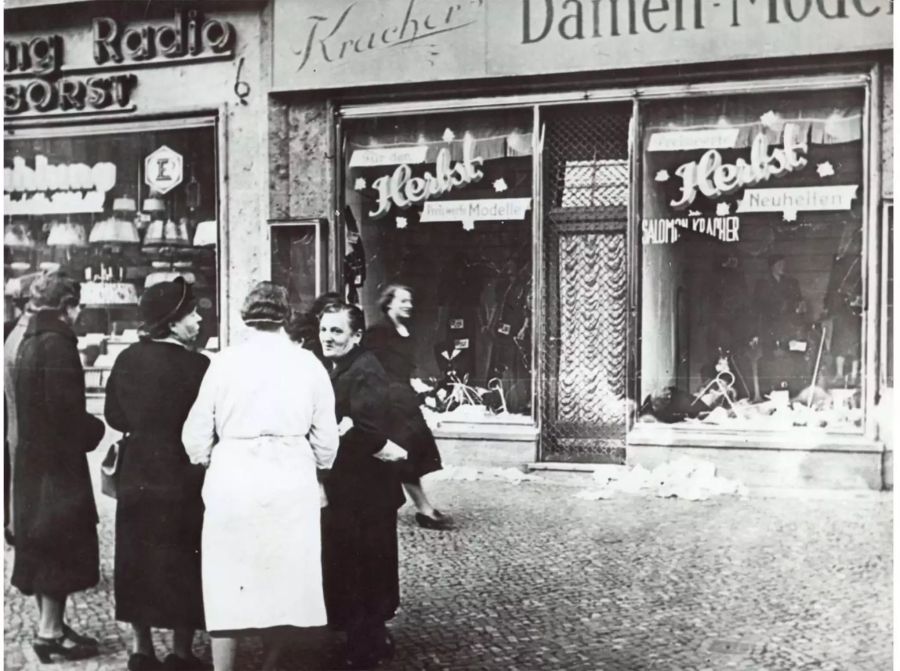 Passanten stehen vor einem jüdischen Modegeschäft, dessen Schaufenster eingeschlagen wurden. Während der sogenannten Reichskristallnacht, vom 9. auf den 10, November 1938, wurden in einer konzertierten Aktion in ganz Deutschland jüdische Geschäfte und Wohnungen verwüstet, Juden verhaftet, misshandelt und umgebracht sowie Synagogen in Brand gesteckt.