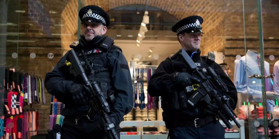 Zwei britische, bewaffnete Polizisten stehen in London am Bahnhof.