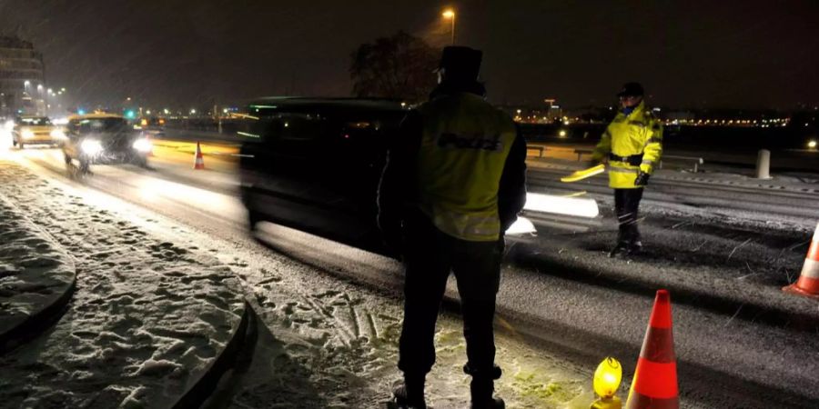 Polizisten stehen am Strassenrand für Personenkontrollen.