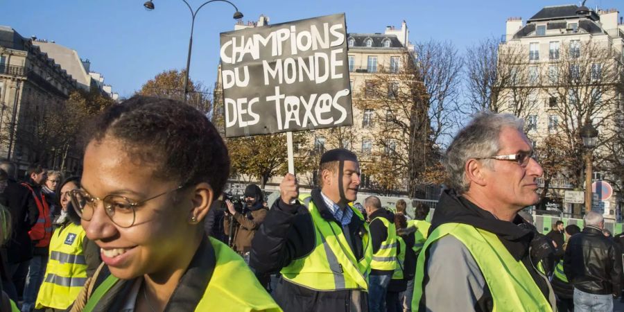 Ein Demonstrant hält ein Schild mit der  Aufschrift "Champions du monde des taxes" (Weltmeister der Steuern) bei einem Protest gegen höhere Spritpreise.