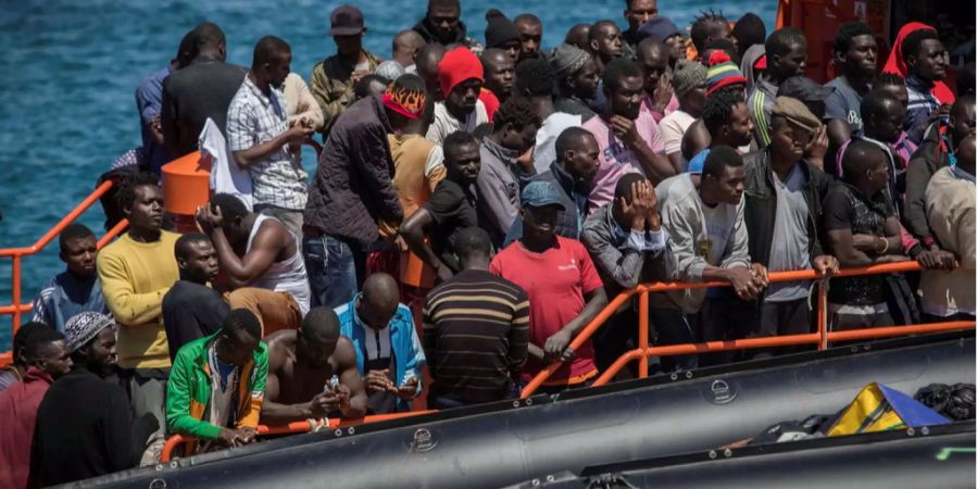 Flüchtlinge an Bord eines Bootes schauen nach rechts. (Symbolbild)