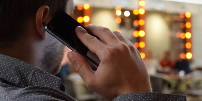 Ein Mann in Australien hält sein Telefon ans Ohr.