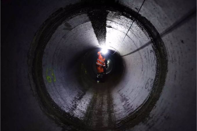 Mitarbeiter mit Stirnlampe in Ablaufleitung in Basler Kläranlage - Keystone Mitarbeiter mit Stirnlampe in Ablaufleitung in Basler Kläranlage - Keystone